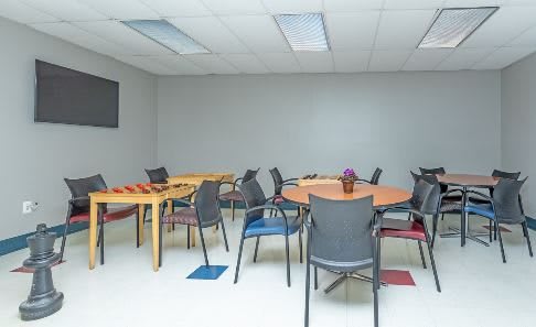 A meeting room with several round and rectangular tables surrounded by chairs.