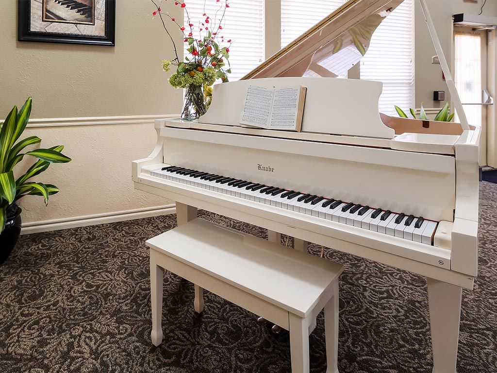 A white piano with a matching bench is elegantly placed in a decorated living room.