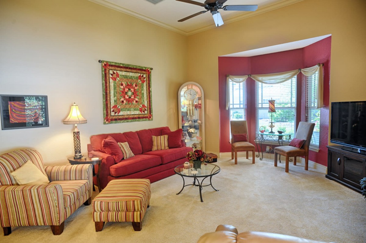 A cozy living room with a red sofa, matching decor, and large windows.