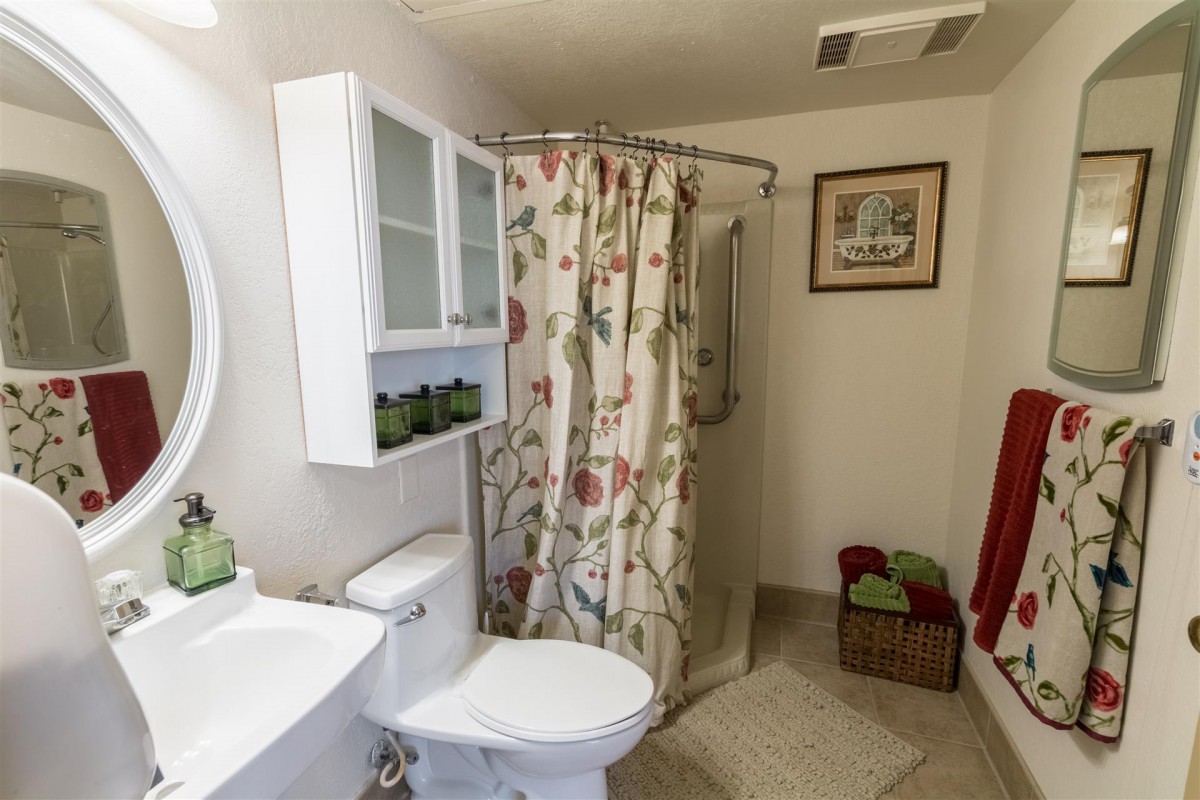 A cozy bathroom with floral shower curtain and neatly arranged towels.