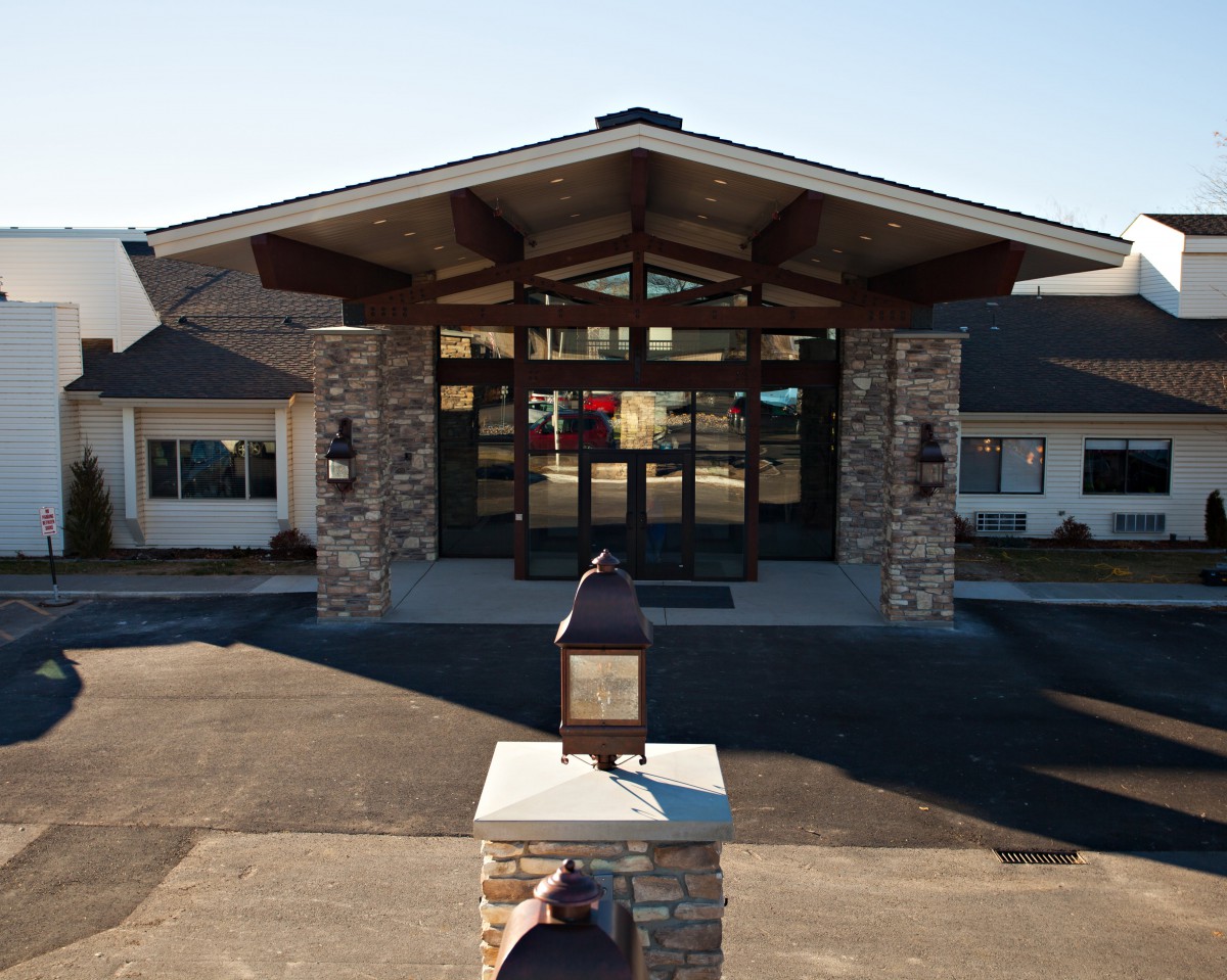 A modern building entrance with stone pillars and a broad roof.