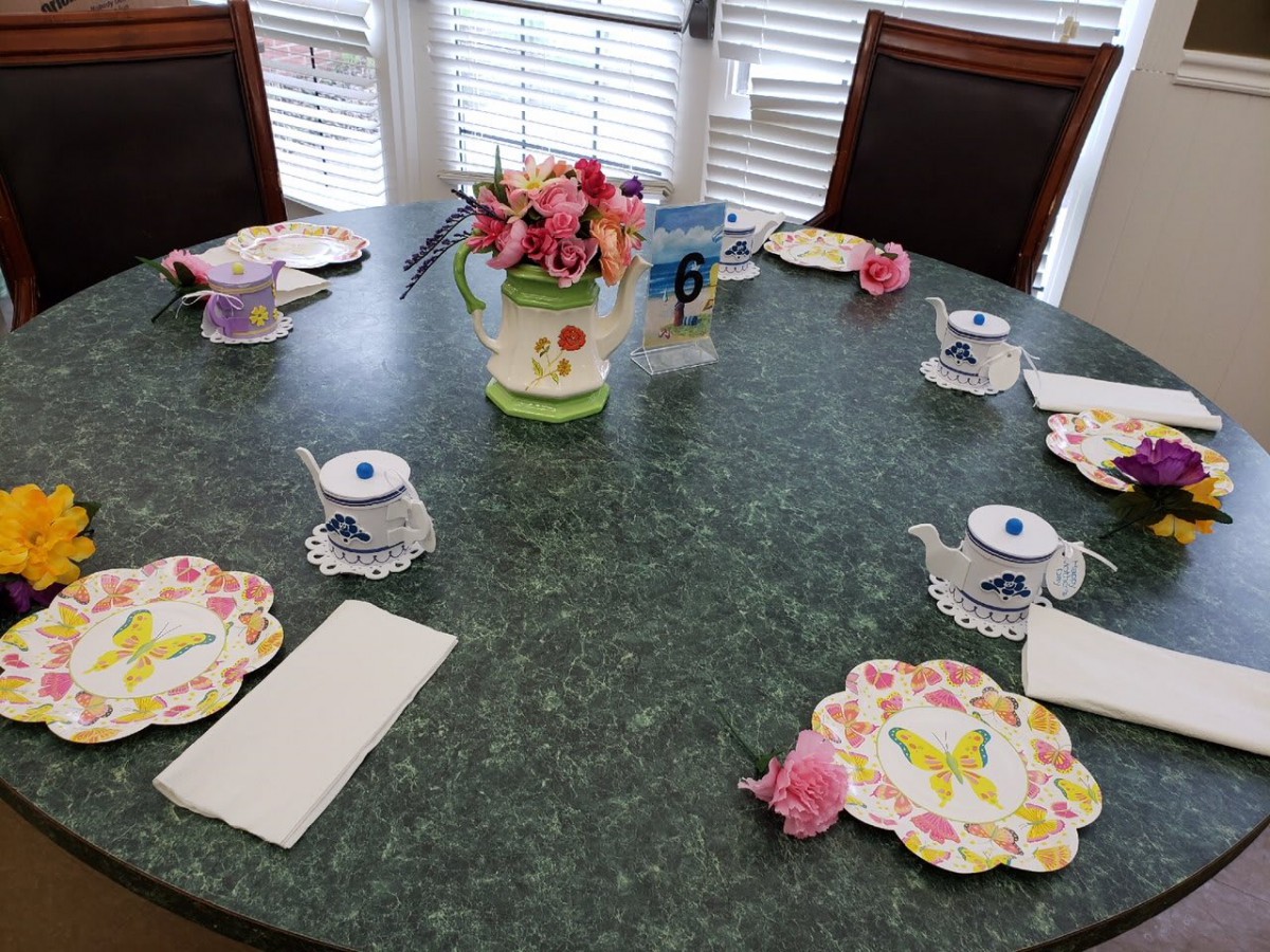 A beautifully arranged table set for a tea party with floral decorations and teapot-themed place settings.