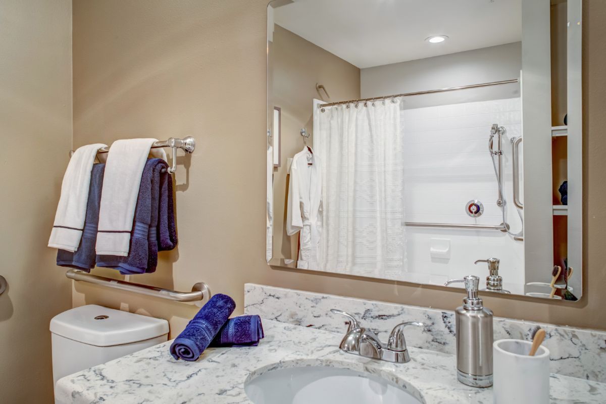A tidy bathroom featuring a mirror, sink, and neatly arranged towels.