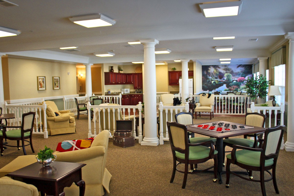 A spacious and well-lit interior featuring a lounge area with seating, dining tables, and a kitchenette.