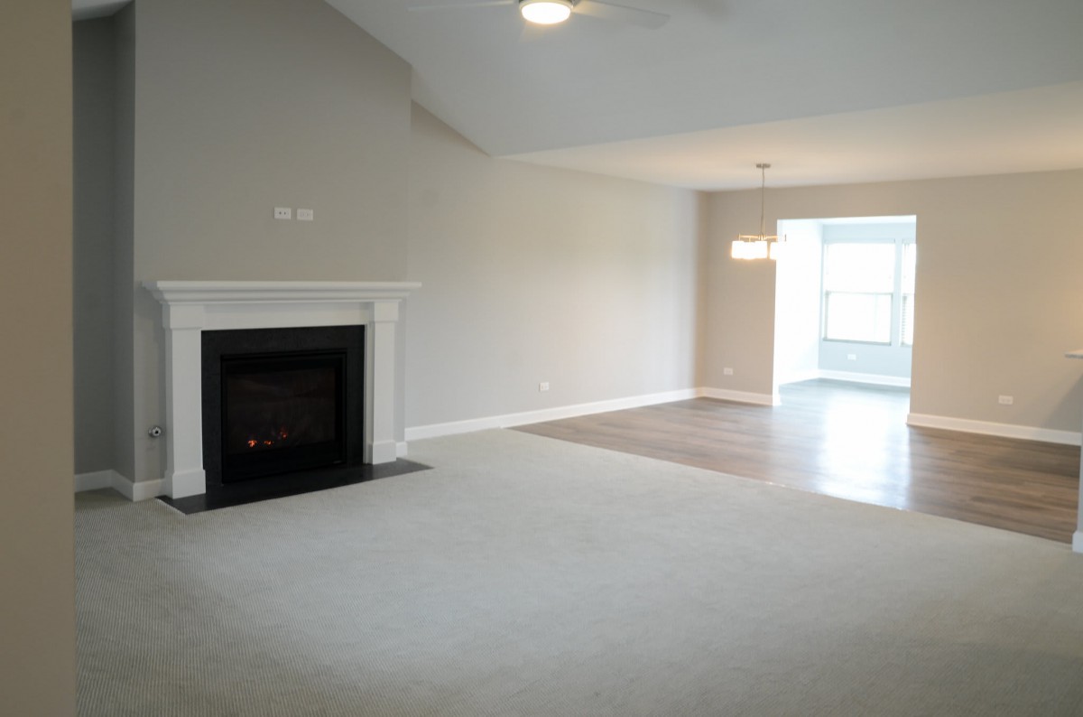 A spacious empty living room with a fireplace and adjacent dining area.