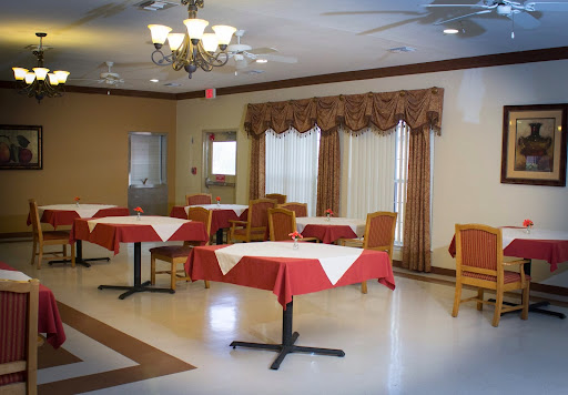 A spacious dining area featuring tables with red tablecloths and elegant curtains.