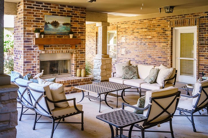 A cozy outdoor patio with comfortable seating and a brick fireplace.