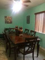 A cozy dining room with a wooden table and chairs, decorated with vases and artwork on the walls.