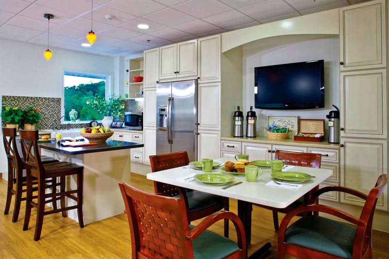 A modern kitchen and dining area featuring sleek appliances, a large refrigerator, and a neatly set dining table.