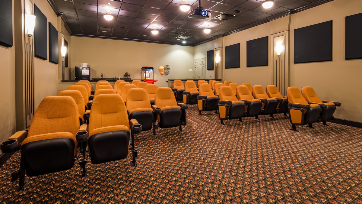 A cozy movie theater with orange seating and a projector.