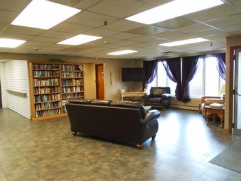 A cozy library lounge with bookshelves, seating area, and a television.