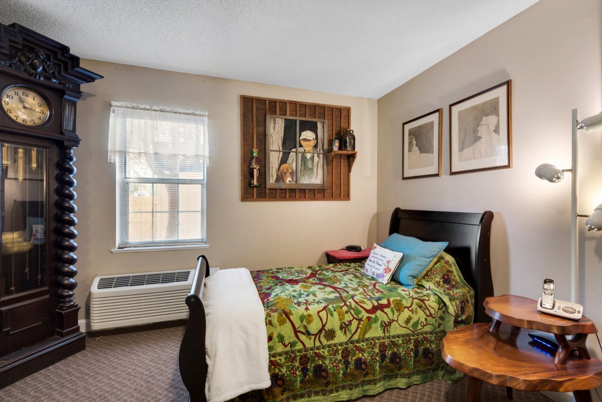 Cozy bedroom with single bed, colorful bedding, and artwork on the walls.