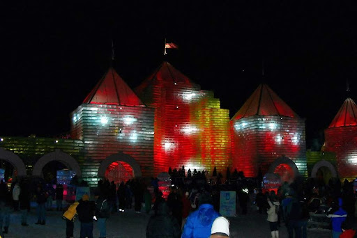 A vibrant ice structure illuminated with colorful lights during a night festival.