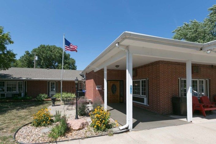 A brick building entrance with an American flag flying on a clear day.