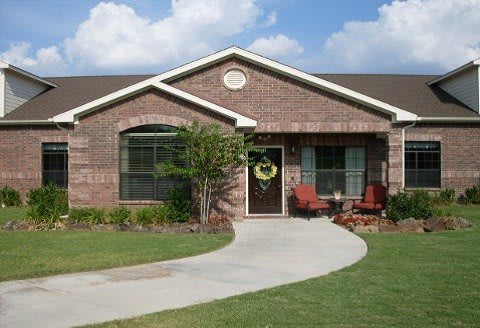 A single-story brick house with a front yard and a curved concrete pathway.
