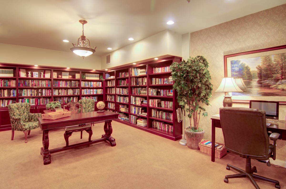 A cozy library with wooden bookshelves, a reading table, and comfortable lighting.