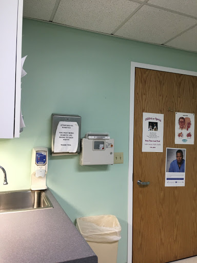A view of a hospital or clinic interior, featuring a green wall, medical information posters, and a door.