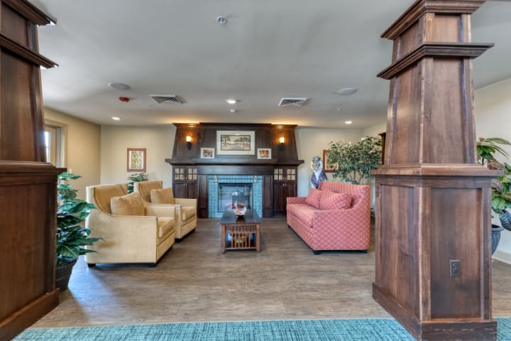 A cozy living room with sofas, a fireplace, and wooden accents.