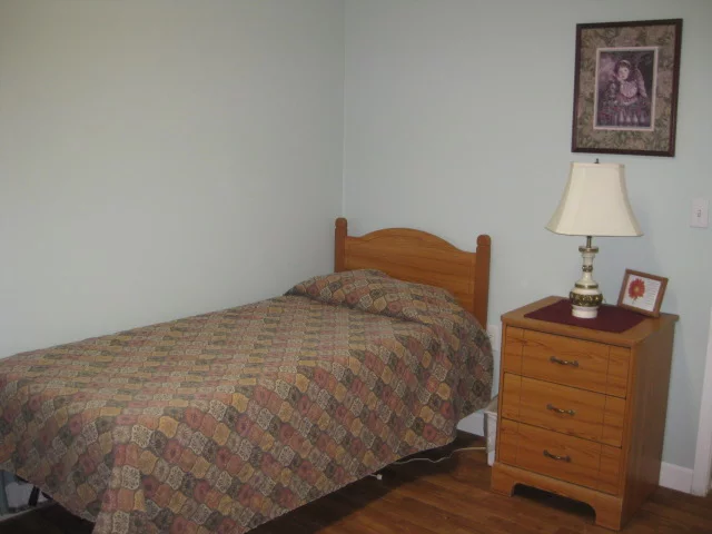 A small bedroom with a single bed and wooden furniture.