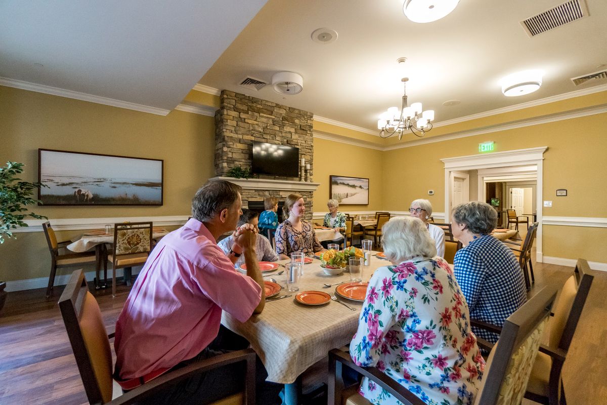 A group of people sitting around a dining table enjoying a meal and conversation in a warmly decorated room.