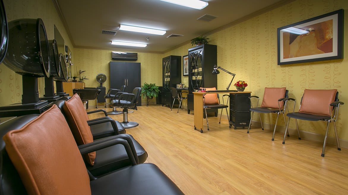 A modern hair salon interior with chairs, desks, and wooden flooring.