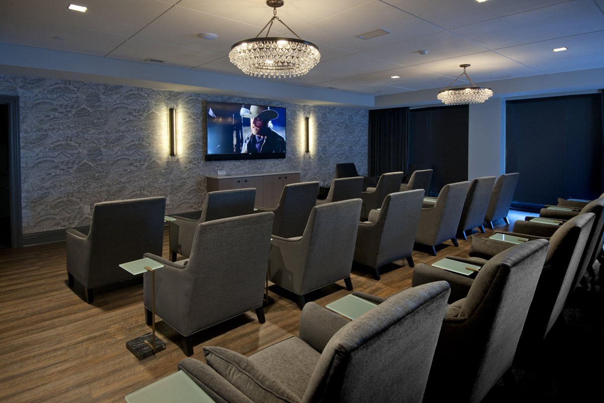 A modern home theater room with comfortable seating and a large TV screen.