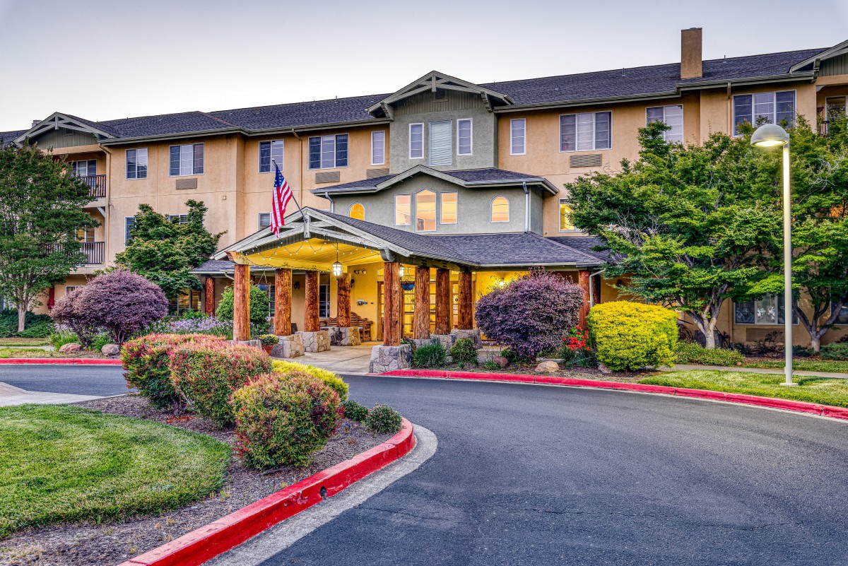 The entrance to a well-lit hotel with landscaped surroundings.