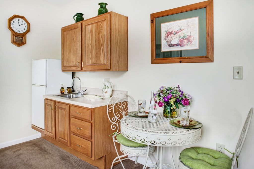 A cozy kitchen area with wooden cabinets and a small dining table adorned with flowers.