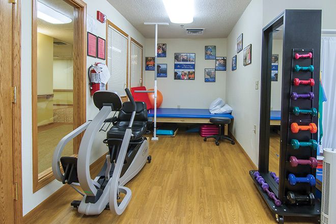 A small gym with exercise equipment and a large mirror on the wall.