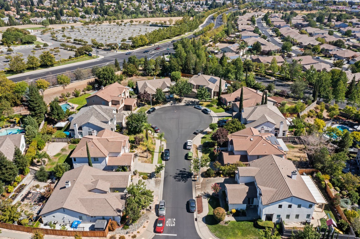 Aerial view of a suburban neighborhood featuring a cul-de-sac with houses and greenery.