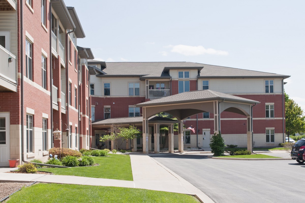 A modern retirement home with a welcoming entrance and landscaped surroundings.