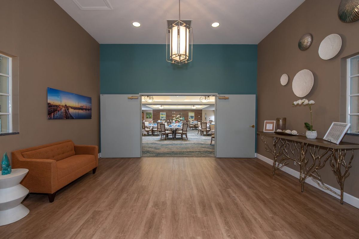 A modern lobby featuring a wooden floor, elegant chandelier, and contemporary decor.