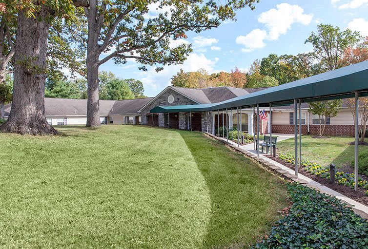 A scenic view of a building surrounded by lush green lawns and trees under a clear sky.
