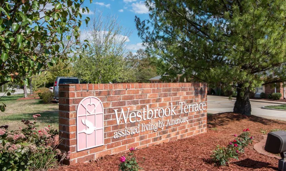 A brick sign for Westbrook Acres Assisted Living & Memory Care surrounded by a landscaped garden.