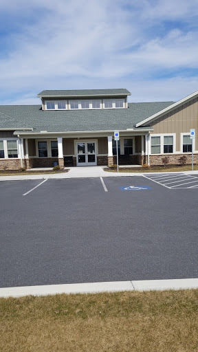 A view of the entrance to a modern building with a parking lot.