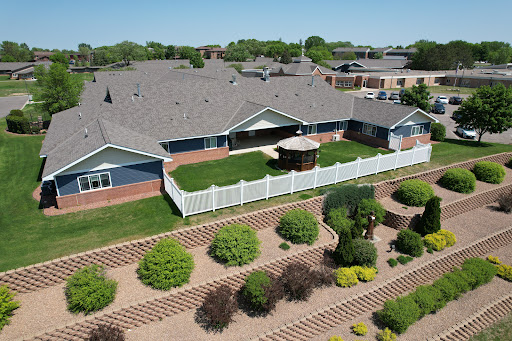 Aerial view of a well-maintained residential property featuring landscaped gardens and a fenced outdoor area.