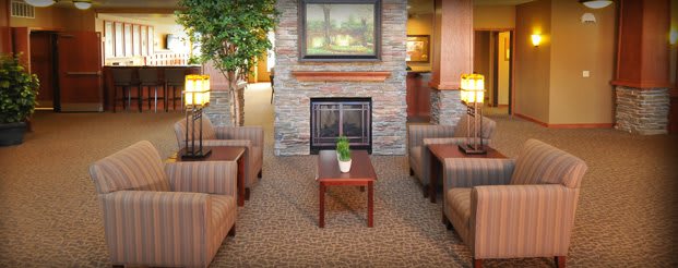 A cozy living room with a central fireplace, comfortable seating, and warm lighting.
