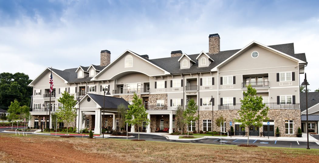 A multi-story residential building with a classic architectural design, featuring balconies and landscaped surroundings.