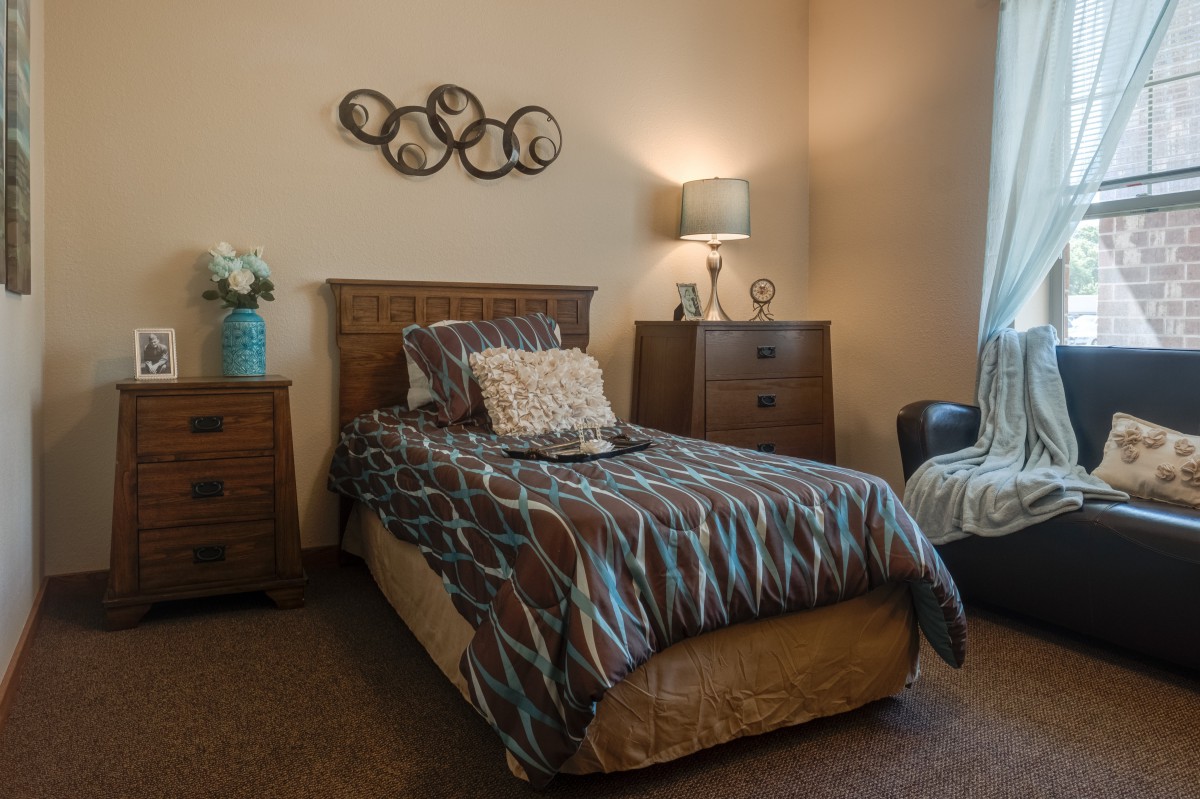 A cozy bedroom with a single bed and warm lighting.