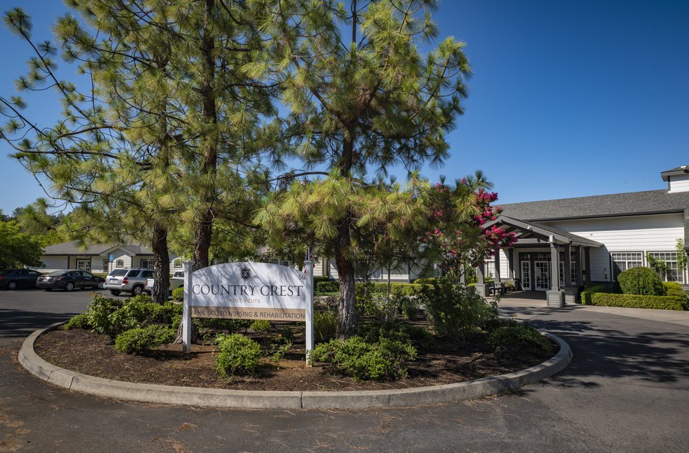 A building entrance surrounded by trees and landscaping under a clear blue sky.