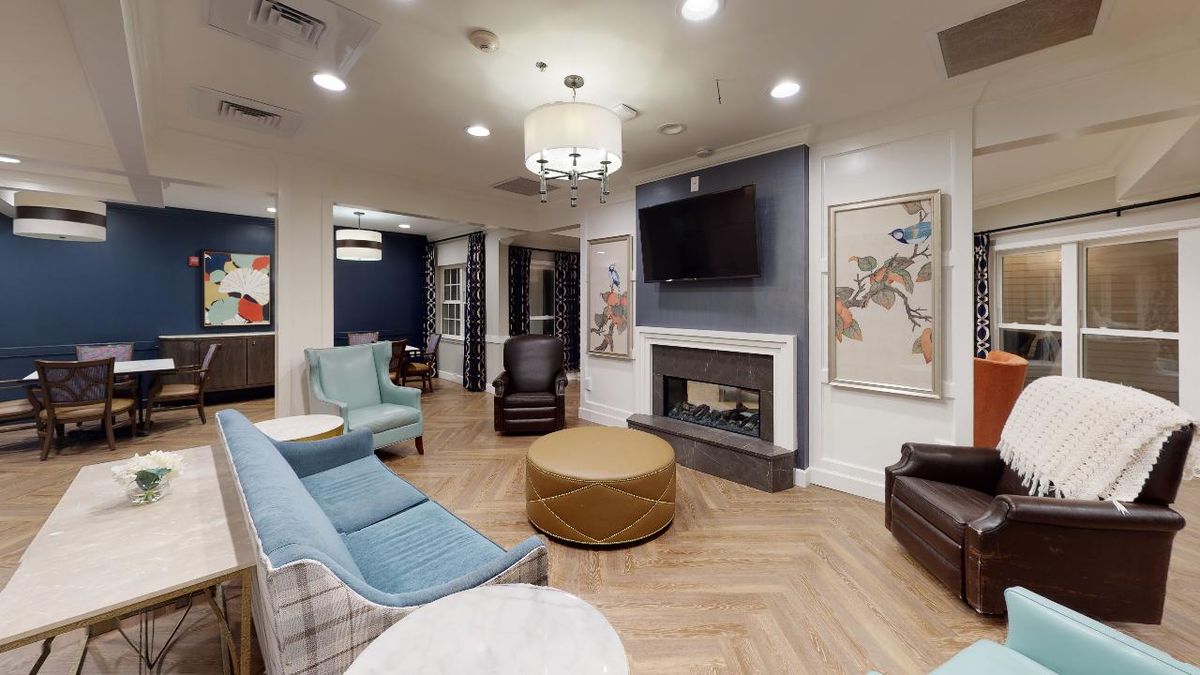 A modern living room with cozy seating, a fireplace, and a mounted television.