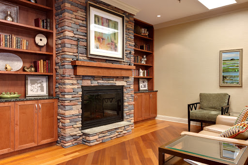 A stylish living room featuring a stone fireplace, wooden bookshelves, and contemporary furnishings.
