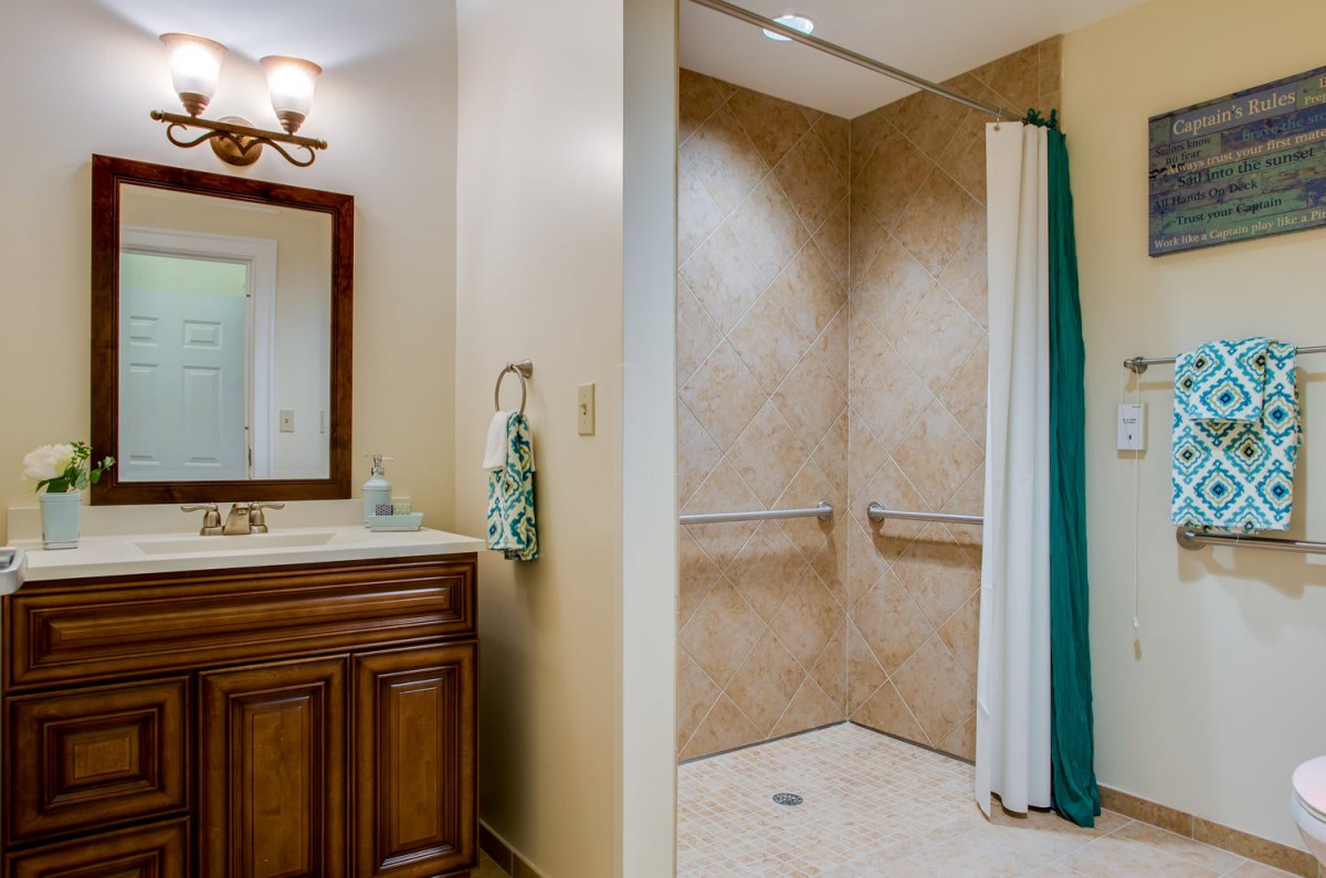 A bathroom featuring a sink with a mirror and an accessible walk-in shower.