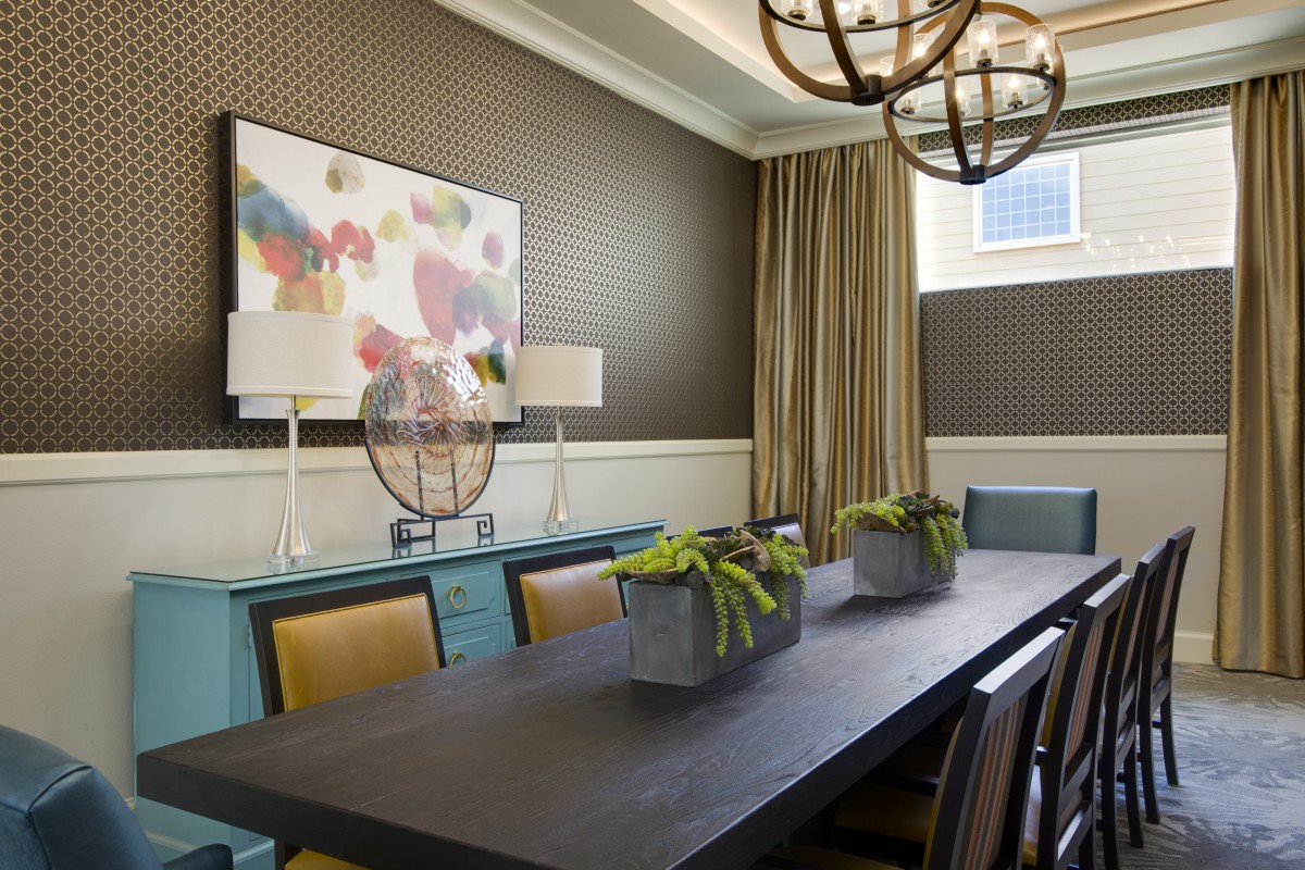 A modern dining room with a long table, decorative plants, and contemporary artwork.
