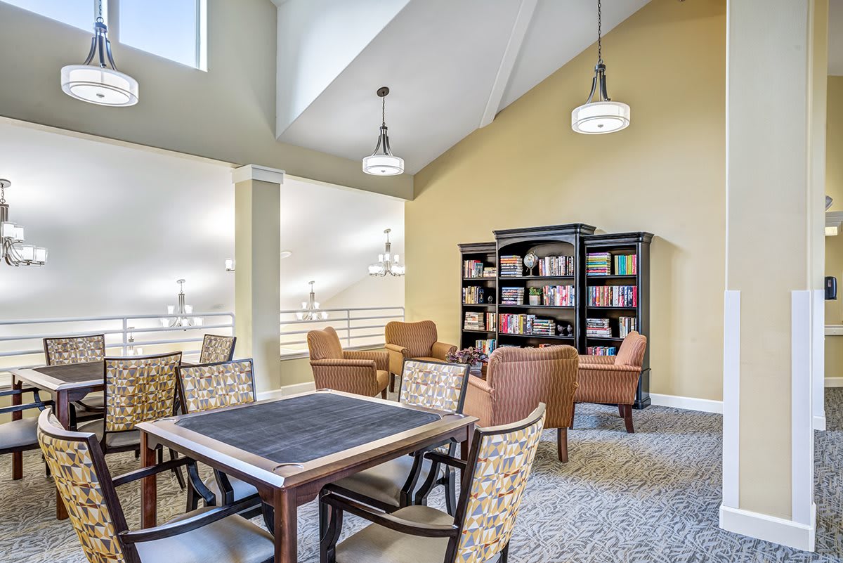 A cozy library reading area with comfortable chairs and a bookshelf under soft lighting.