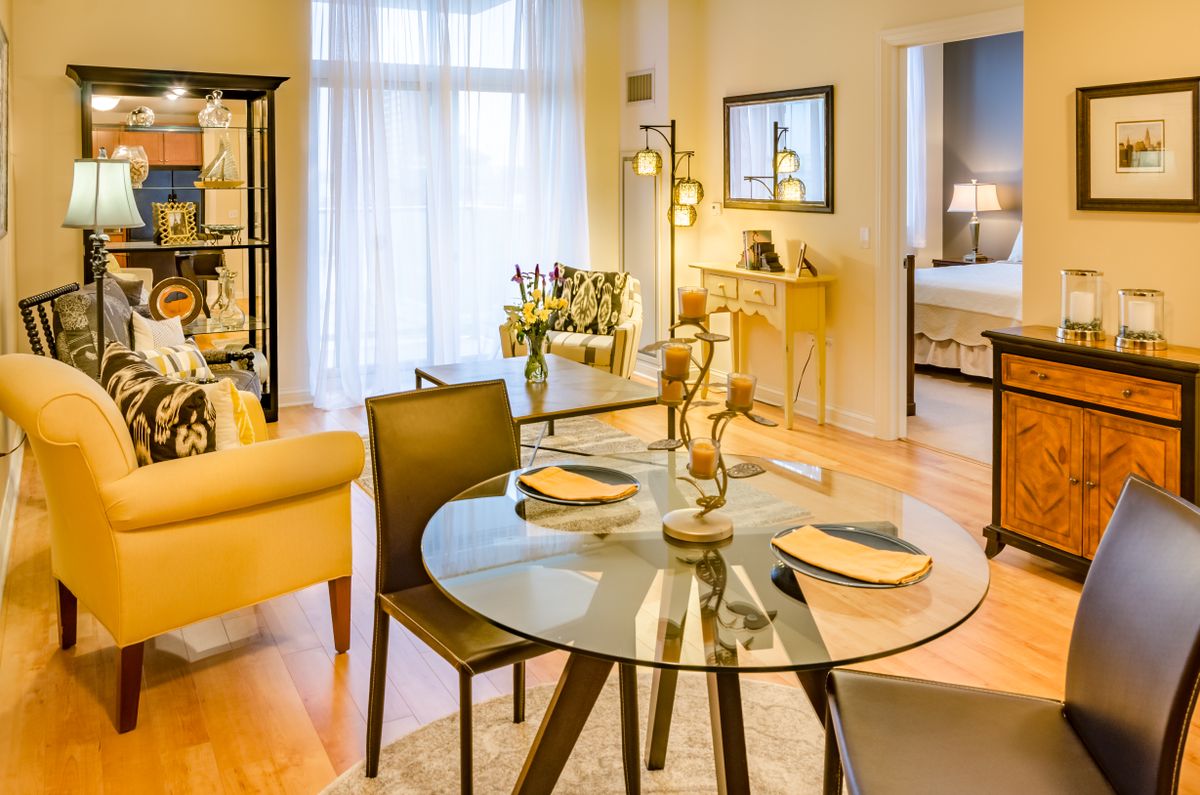 A modern living room with a glass dining table, cozy seating, and elegant decor.