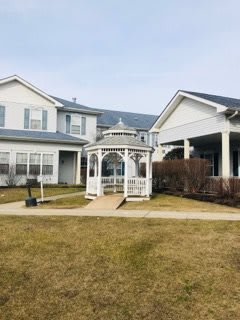 A small white gazebo in the yard between two residential buildings.