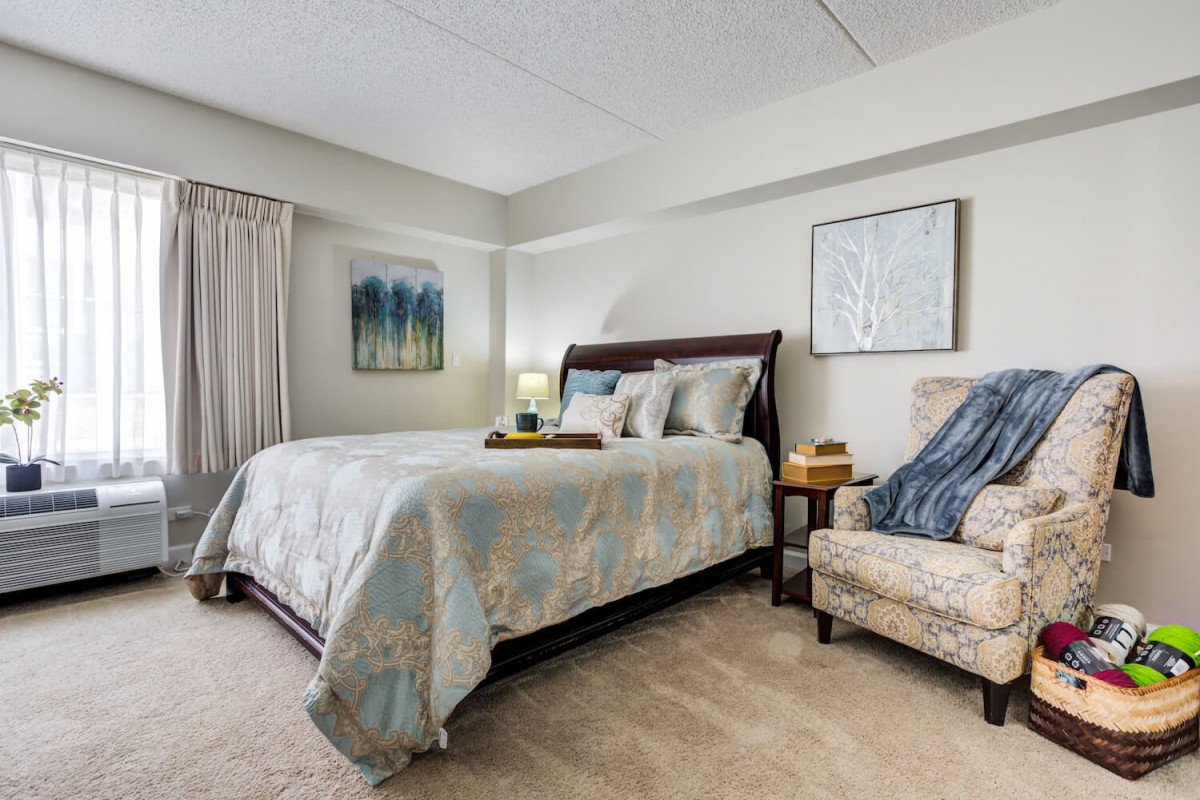 A cozy bedroom with a double bed, bedside lamp, and artwork adorning the walls.