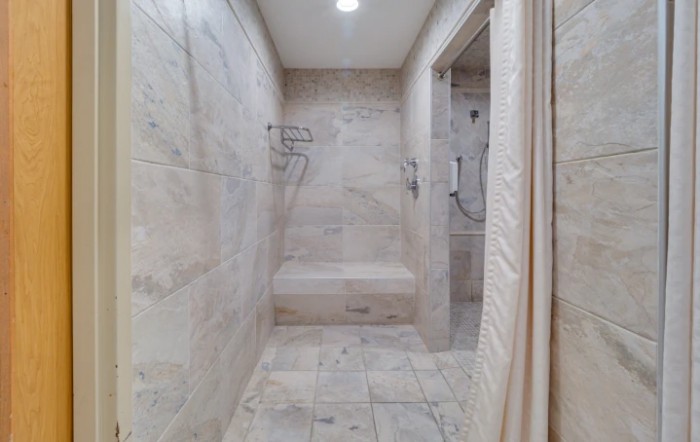 A modern marble-tiled walk-in shower with a built-in bench.