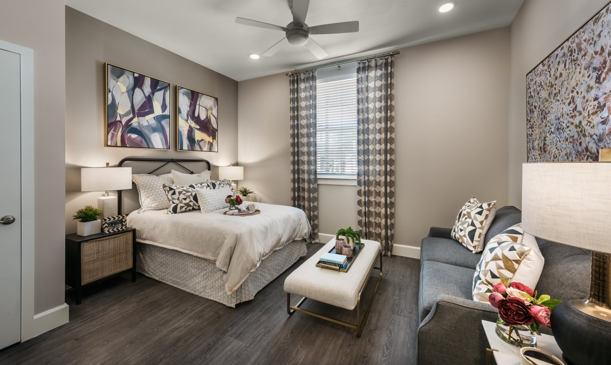 A modern bedroom interior featuring a cozy bed, stylish artwork, and contemporary furnishings in neutral tones.